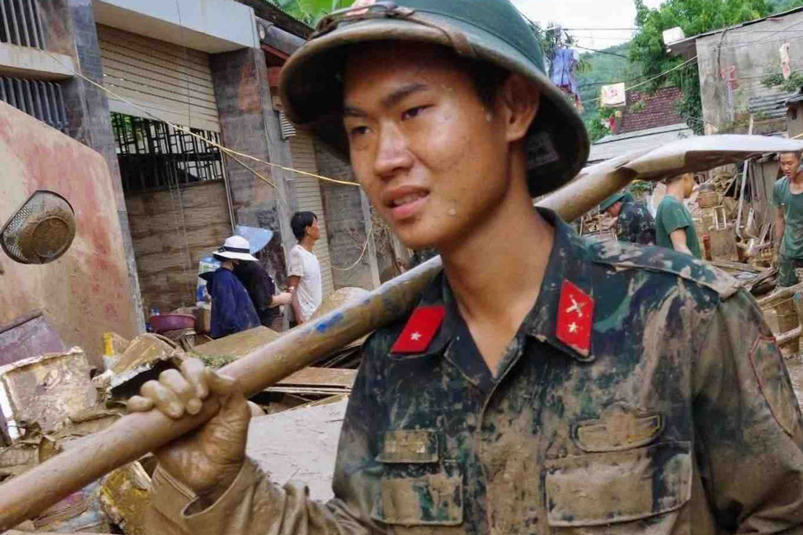 Des soldats de la region militaire 4 luttent contre la boue pour aider les habitants a surmonter les consequences des inondations. Photo : Hong Thai