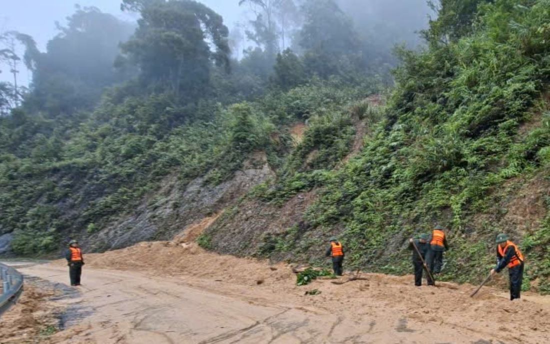 Les gardes-frontieres nettoient la terre et les pierres a cote du point de glissement de terrain sur la route Ho Chi Minh nhanh Tay. Photo : H.Nguyen