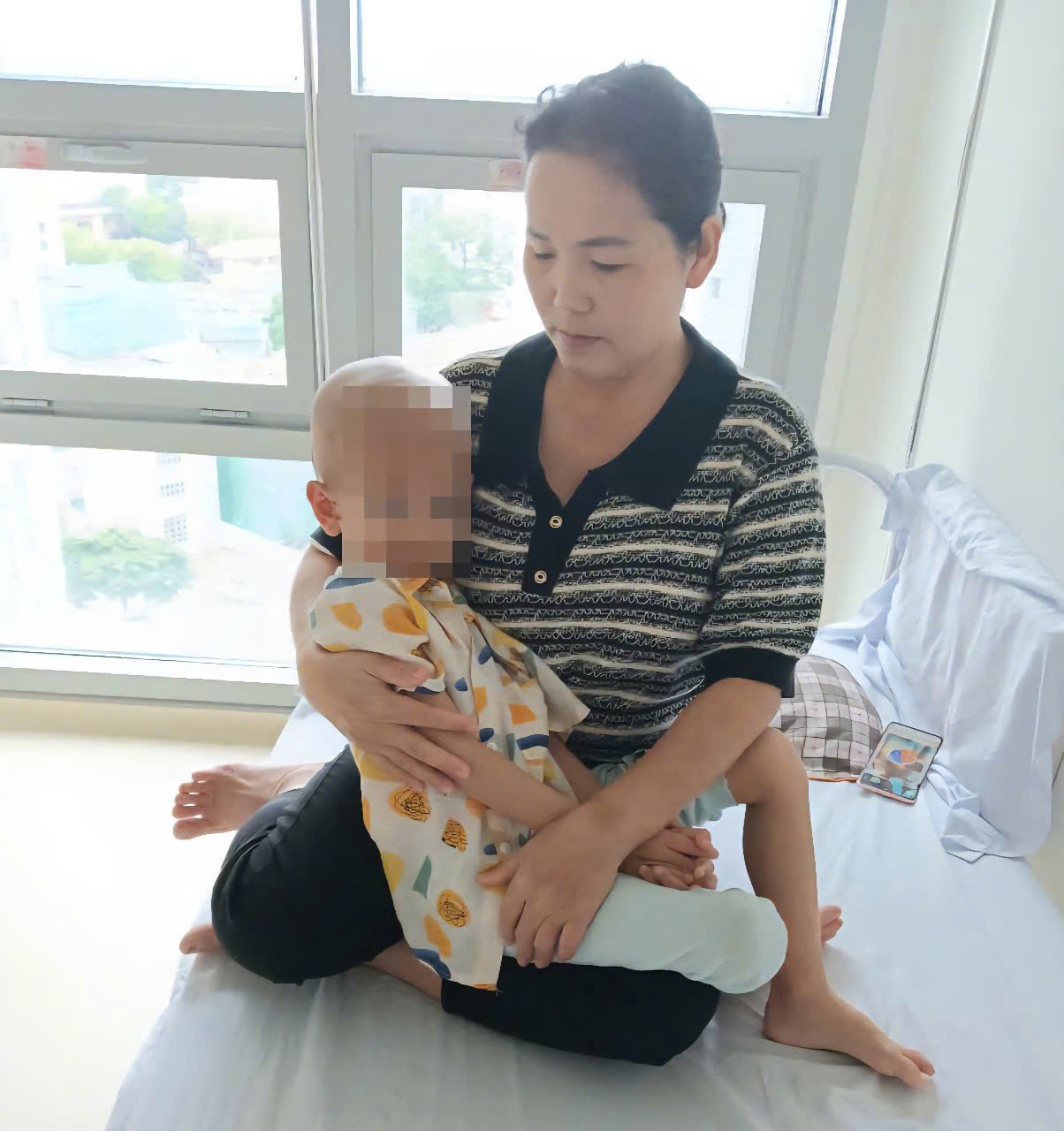 Avec 2 garçons atteints du meme cancer Mme Nguyen Thi Tam est confuse car elle n'a pas d'argent pour soigner ses enfants. Sur la photo Mme Tam porte son enfant Phan Xuan Phuc pendant son traitement a l'hopital. Photo : Nguyen Tam
