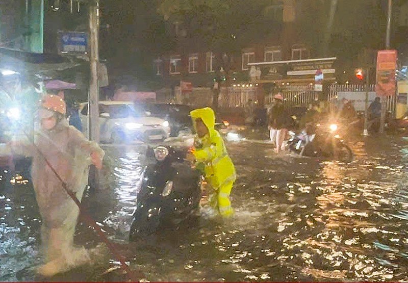 다낭 시민과 교통 경찰은 폭우와 갑작스러운 정전으로 인해 위험한 지점을 안전하게 통과하는 교통 참여자를 지원합니다. 사진: CACC