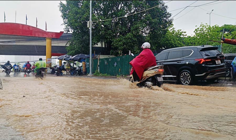 Mua lon kem theo bun dat tu cong truong khien khu vuc duong Dinh Thon ngap sau, nguoi dan gap kho khan khi di chuyen. Anh: Hai Danh