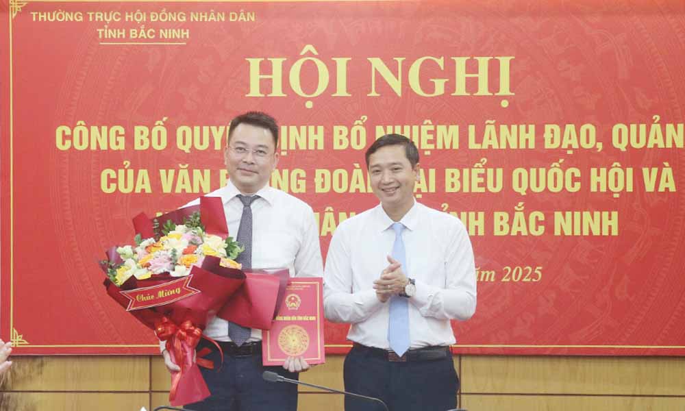Bac Ninh省人民評議会のNguyen Viet Oanh委員長が決定を授与し、Nguy Van Tuyen氏に花束を贈呈。写真:Bac Ninh新聞