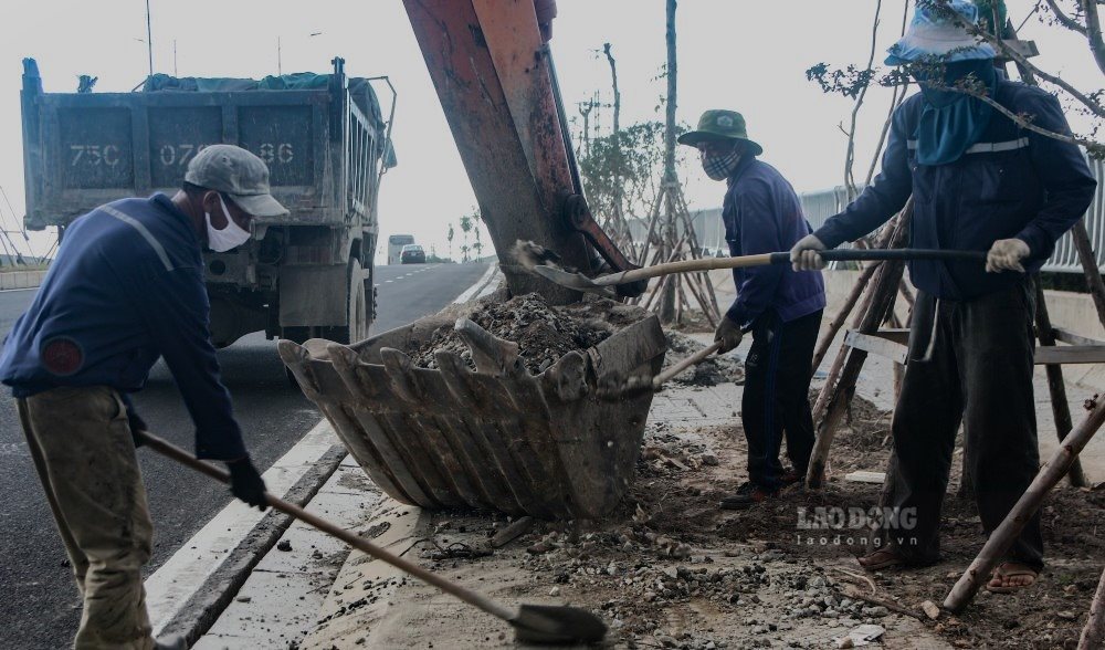 Cac cong nhan tat bat voi cong tac don dep hai ben le duong.