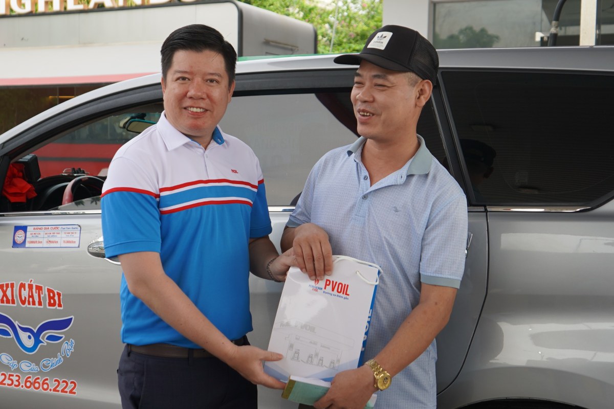 Trong sang 1.8, nhung vi khach dau tien tin dung xang E10 duoc nhan phan qua tu dai dien PV OIL. Ảnh: Mai Dung