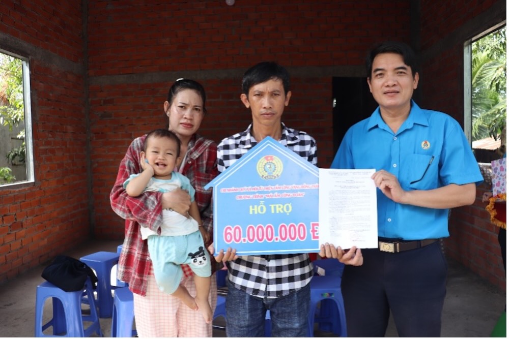 Ong Pham Vo Duc Trung - Uy vien Ban Thuong vu LDLD tinh Dong Thap trao quyet dinh va bang tuong trung ho tro xay dung nha “Mai am Cong doan” cho doan vien Bui Truong Giang. Anh: Luu Hung.