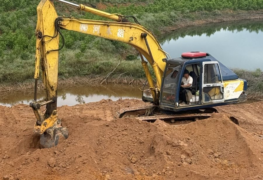 Người dân dùng máy múc san ủi đất lấp kênh thủy mương để lấn chiếm đất công. Ảnh: Hưng Thơ