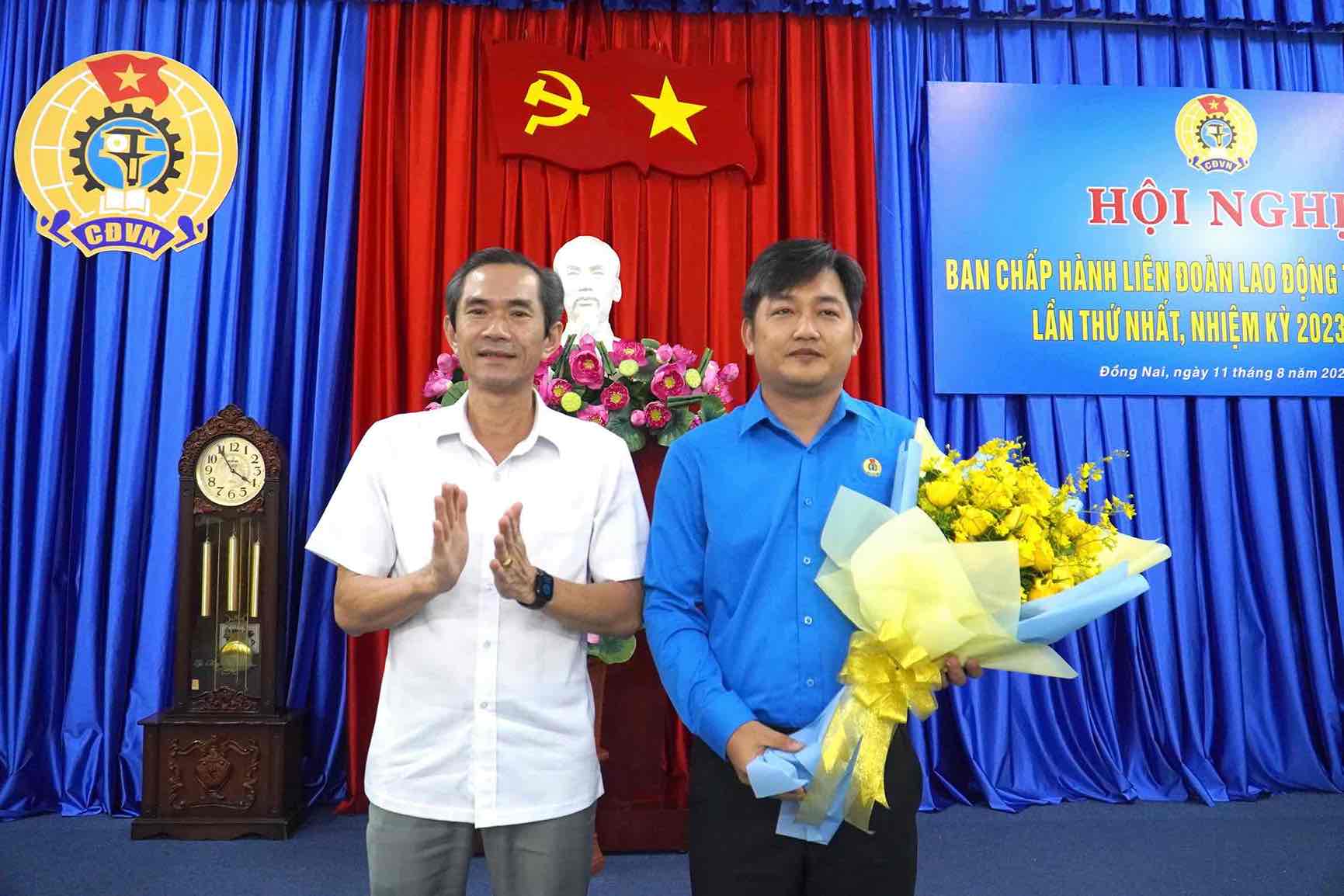 Nguyen Tat Do 동나이성 베트남 조국전선 위원회 부위원장이 Nguyen Quoc Dung 씨(오른쪽)가 동나이성 노동총연맹 위원장으로 선출된 것을 축하하며 꽃을 전달하고 있습니다. 사진: HAC