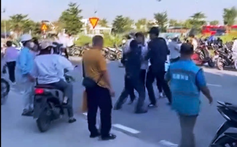 Two men in protective uniforms rushed in to punch and kick a dusty bag, causing a male worker to fall onto the road. Photo cut from clip