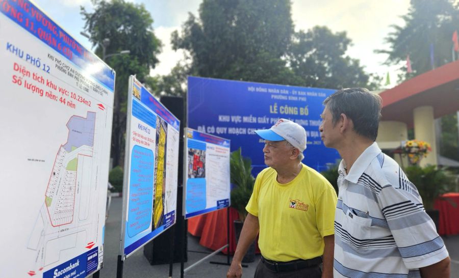 Los residentes del barrio de Binh Phu ven el plan que muestra las areas libres de permisos de construccion. Foto: Sy Dong