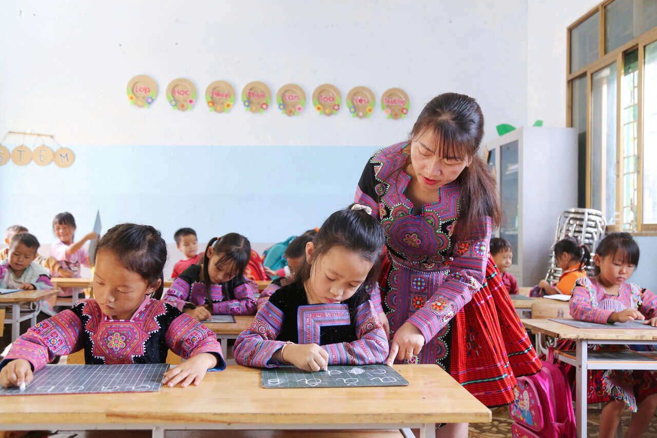 Co Giang Thi Sao, giao vien mon Am nhac vua day tieng Viet, vua tap viet cho cac em hoc sinh vung cao. Anh: Binh Khang