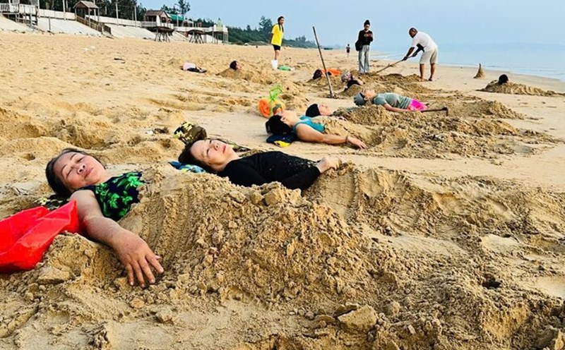 Many people in Quang Ngai believe that the habit of burying themselves in sand in the early morning can help their bone and joint diseases subside. Photo: Ai Vy