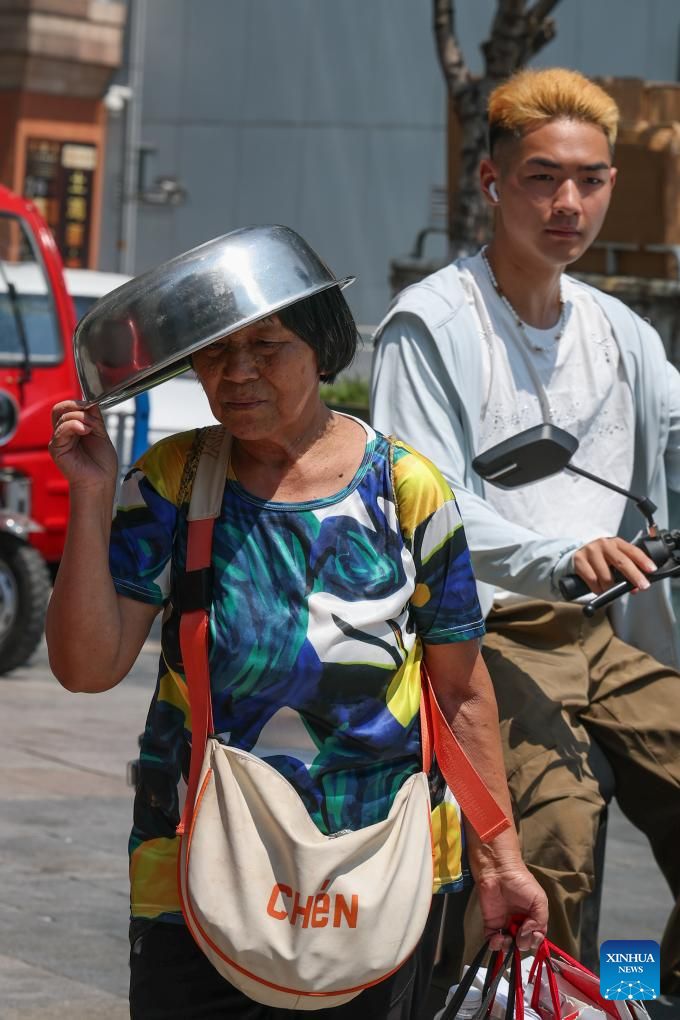 Mot nguoi phu nu dung chau che nang o Trung Khanh ngay 2.8.2025. Anh: Xinhua