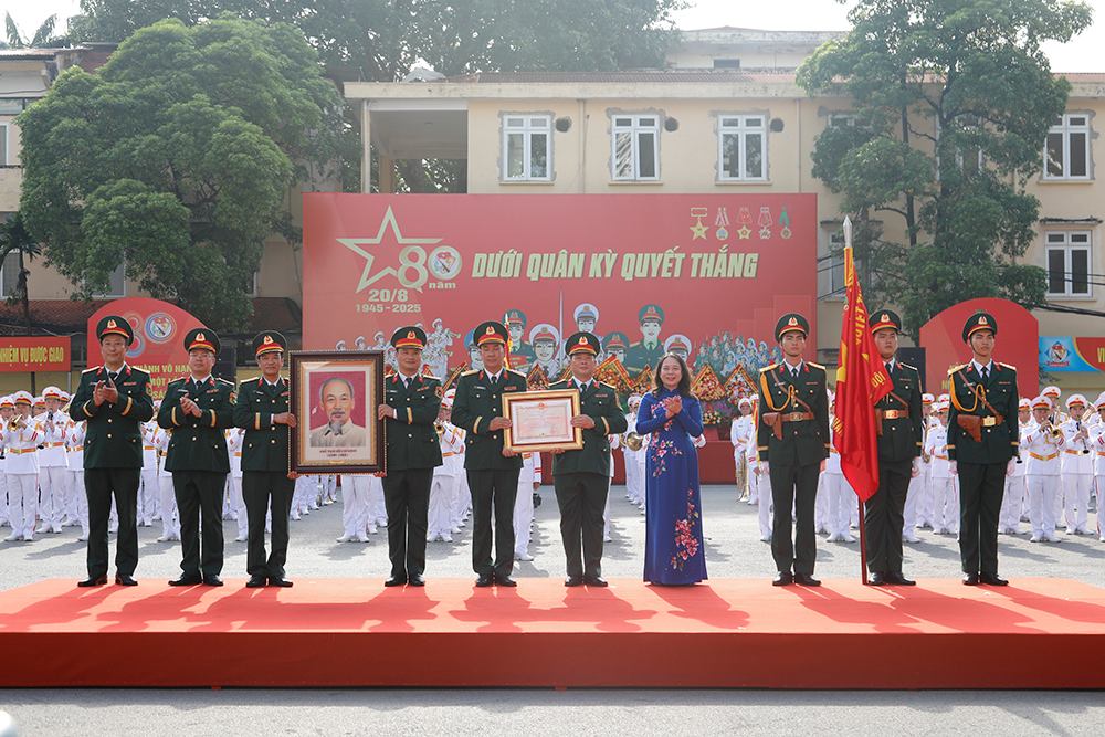 Pho Chu tich nuoc Vo Thi Anh Xuan trao Huan chuong Bao ve To quoc hang Nhi va anh chan dung Chu tich Ho Chi Minh tang Doan Nghi le Quan doi. Anh: Thuy Linh