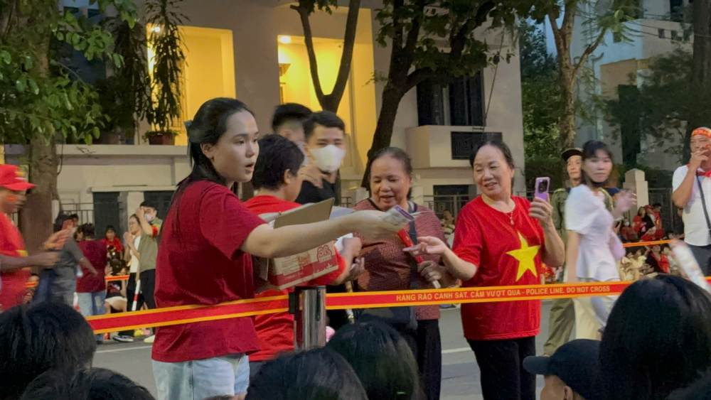 Vo Duy Manh phat do an, thuc uong cho nguoi dan di xem tong hop luyen dieu binh, dieu hanh A80. Anh: Nguyen Dat