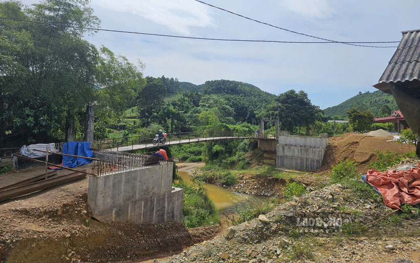 Người dân bất chấp nguy hiểm hàng ngày vẫn đi qua cầu treo xuống cấp, cạnh cầu mới xây dựng dở dang. Ảnh: Văn Đức 
