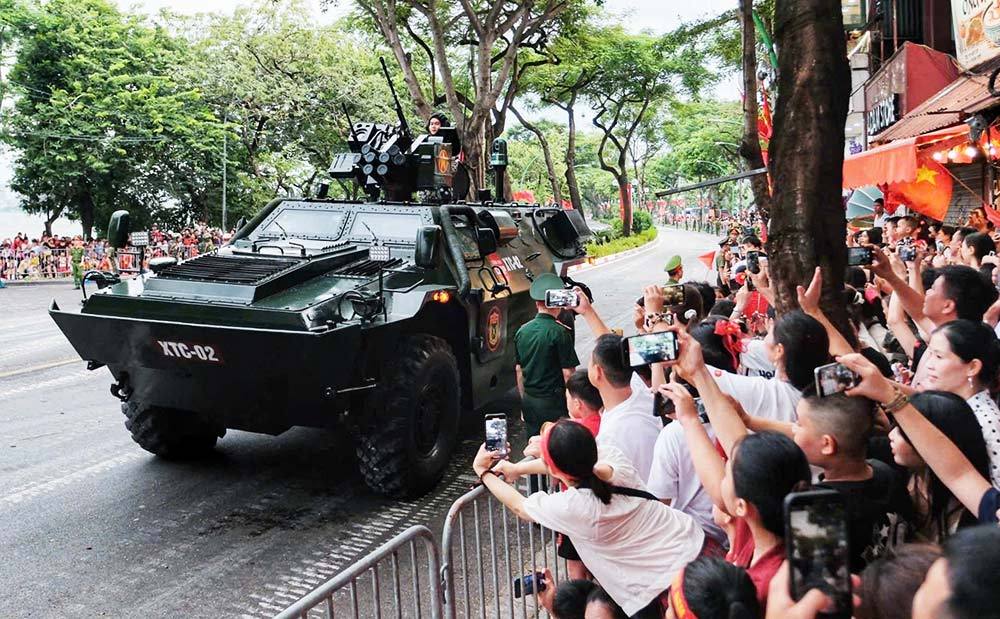 La gente saluda al vehiculo blindado que transporta al ejercito XTC-02 que pasa por la calle Thanh Nien hacia el punto de reunion listo para participar en la sesion de entrenamiento general de la noche del 24 de agosto. Foto: To The