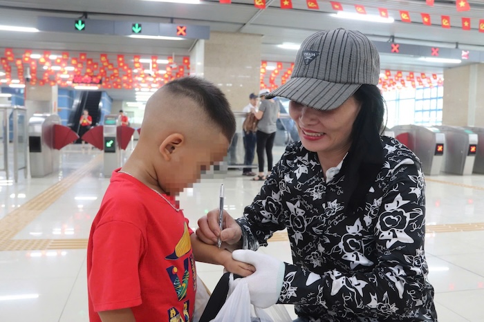 Tourists write their phone numbers on their children's hands while waiting to watch the September 2 parade. Photo: Nguyen Linh