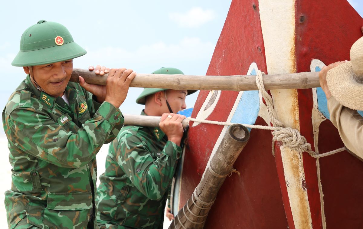 Les gardes-frontieres soutiennent les pecheurs qui montent a terre pour eviter la tempete n° 5. Photo : Hung Tho
