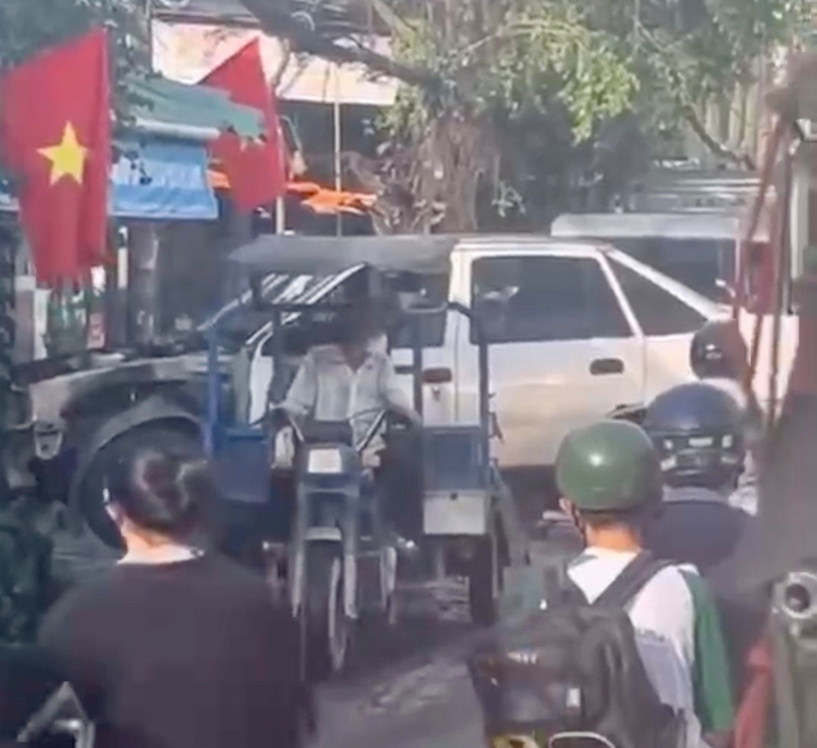 Image of a three-wheeled vehicle driver carrying an old car causing traffic congestion and being fined. Photo: Dong Hoang