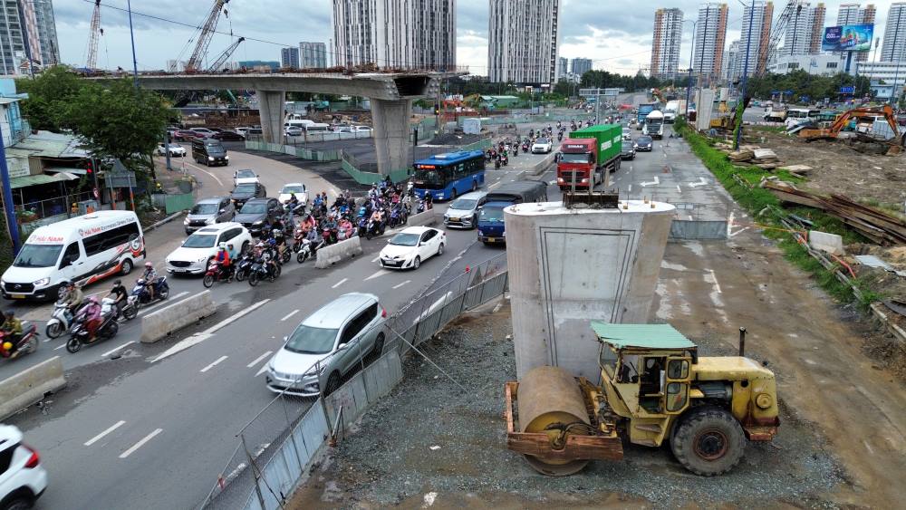   Nhin tu tren cao, cong truong van con nhieu doan im ang, vang bong cong nhan. Xen ke giua khoi be tong, thep do dang la canh tuong hon loan giao thong ben duoi. Cang gan moc ve dich, ap luc tien do cang de nang, trong khi thuc te thi cong van i ach.