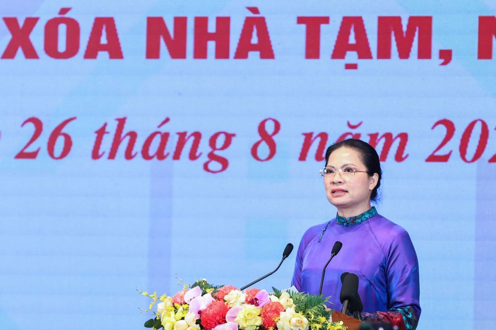 La Sra. Ha Thi Nga - Vicepresidenta del Comite Central del Frente de la Patria de Vietnam informa sobre algunos resultados tipicos del sistema del Frente de la Patria y las organizaciones miembros en el trabajo de eliminacion de viviendas temporales. Foto: Pham Dong