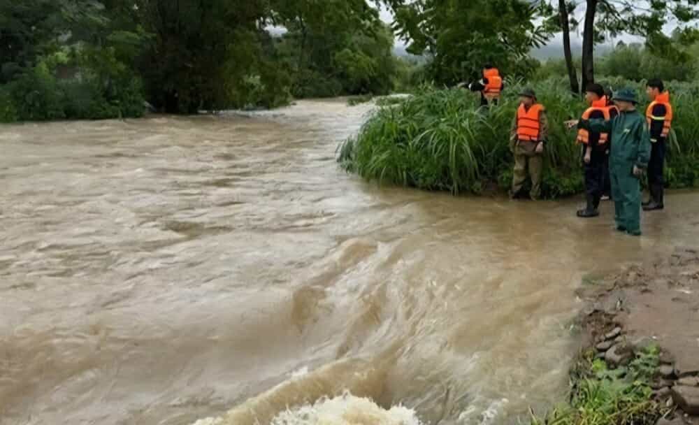 Une femme emportee par les inondations en traversant un deversoir. Photo : Duc Hanh