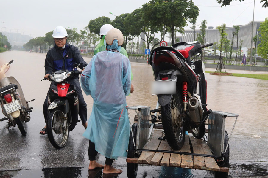 Nhieu nguoi dan phai thue xe keo phuong tien qua diem ngap. Ba Pham Thi T (nguoi lam dich vu keo xe) cho biet, do nuoc ngap sau nen dich vu keo xe may qua diem ngap da tang len 300.000 dong/xe.