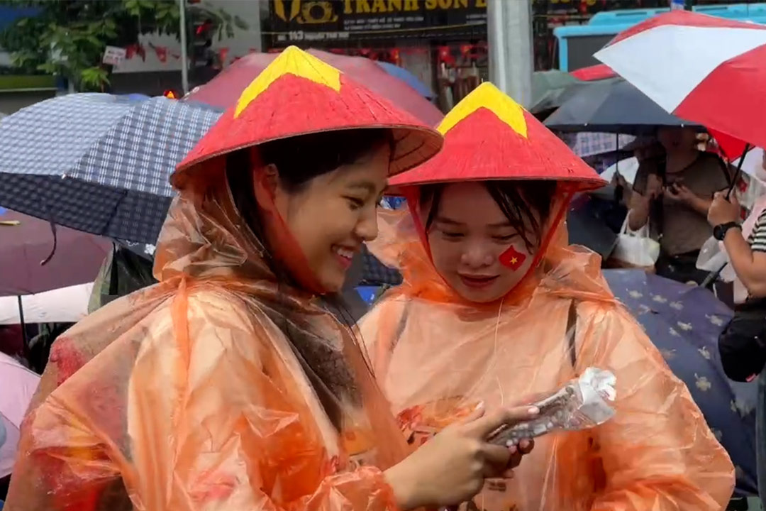Despite the rain and wind, people wear umbrellas and raincoats to watch the parade from 5am
