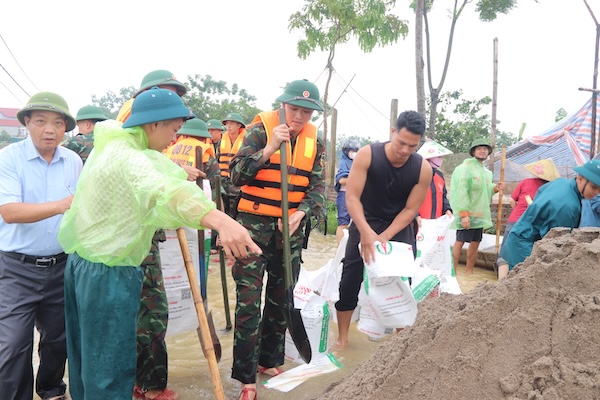 Khong quan ngai kho khan, bun dat, tung bao cat duoc nhanh chong van chuyen, xep chong len nhau, tao thanh nhung buc tuong kien co chan dong nuoc lu dang cuon cuon chay. Anh: Nguyen Linh