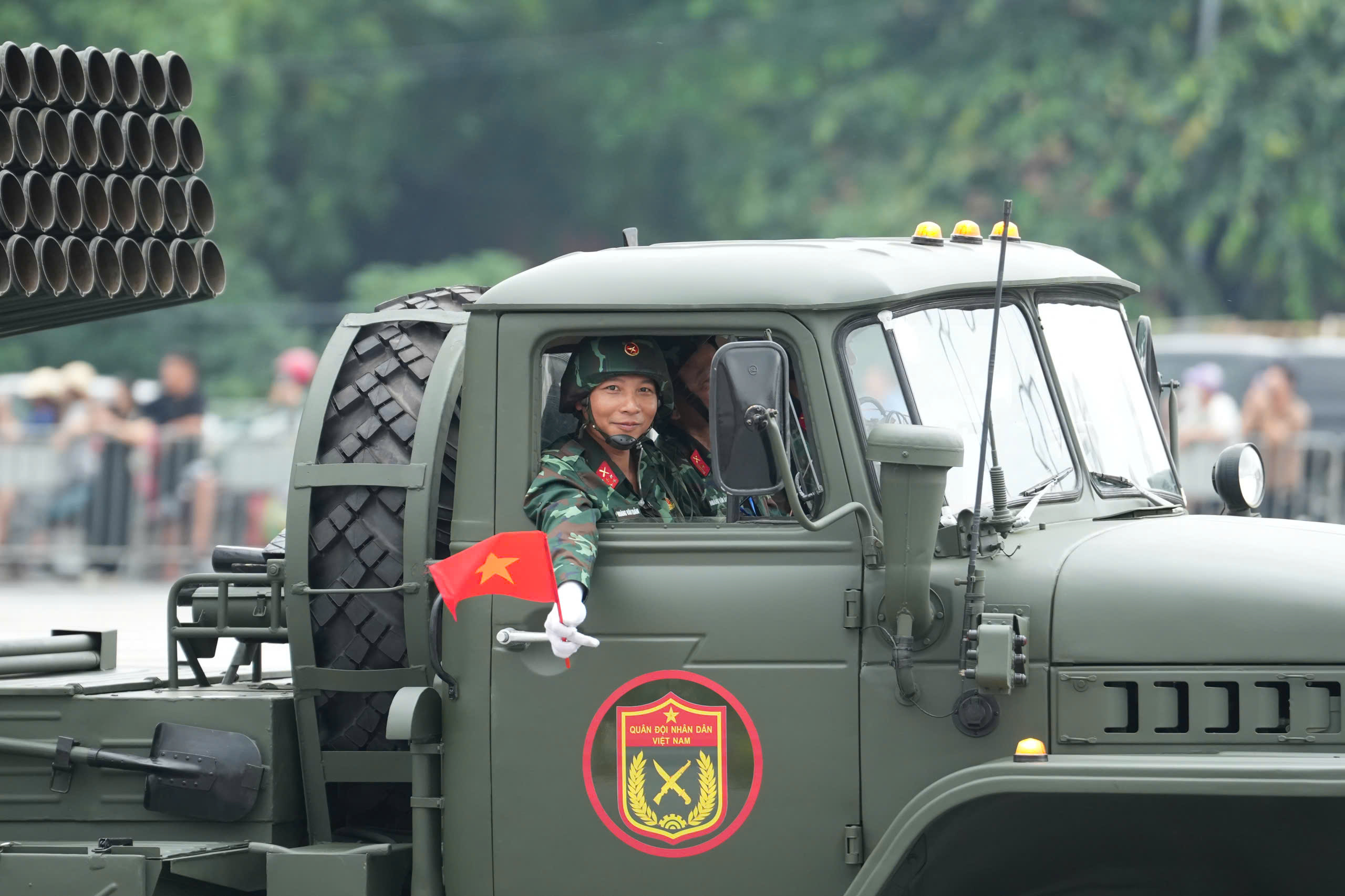 16h30: Doan xe phao Quan su banh lop, xe dac chung Cong an xuat phat tu Truong dua F1 vao trung tam thanh pho de so duyet dieu binh, dieu hanh  dip ky niem 80 nam Quoc khanh.  Den khoang 16h45, troi do mua lon, nhieu nguoi che o, mac ao mua de tiep tuc theo doi doan xe di chuyen.  Tieng loa phat ra tu dan khi tai: “Cam on ba con, chuc ba con khoe“. Nguoi dan lien tuc vay tay, ho reo dap lai tinh cam cua can bo, chien si Quan doi va Cong an. Anh: Huu Chanh