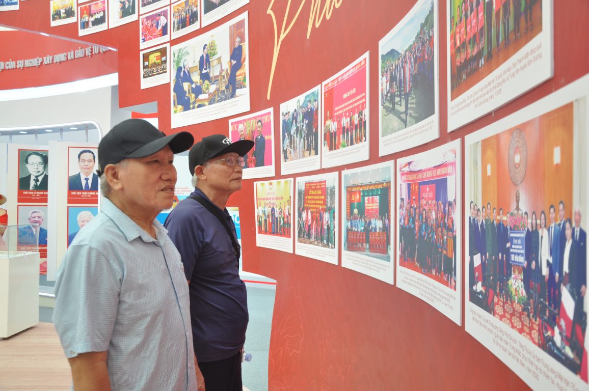 Ong Le Huu Toan (ngoai cung ben trai) tim hieu thong tin tai khong gian trien lam Mat tran To quoc Viet Nam. Anh: Bao Han