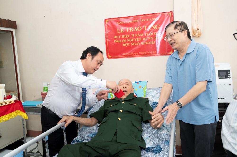 Bi thu Dang uy phuong Tan Son Nhat Le Hoang Ha trao Huy hieu Dang cho cu ong lon tuoi tai nha. Anh: Minh Tan