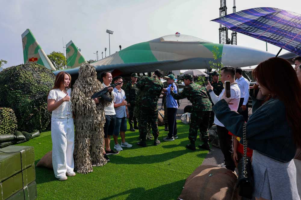 Khach tham quan trai nghiem cam giac mac quan phuc nguy trang cua Quan doi Viet Nam duoi tiet troi nang nong.