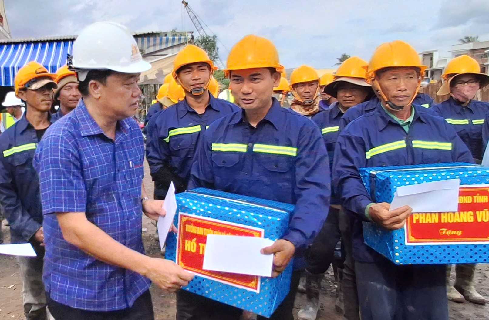 M. Huynh Quoc Viet secretaire adjoint permanent du Comite provincial du Parti et president du Comite MTTQ de la province de Ca Mau (portant un chapeau blanc) offre des cadeaux aux ouvriers sur le chantier. Photo : Nhat Ho