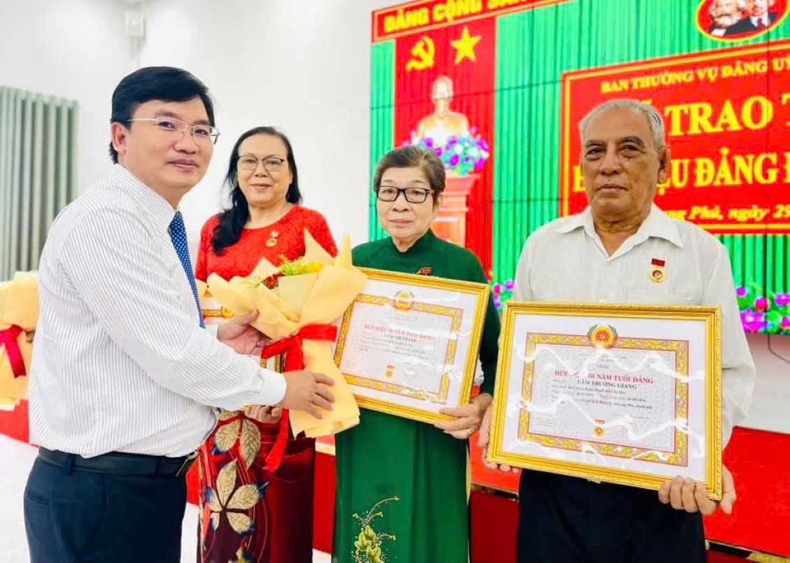 Ong Lam Tien Thach, Thanh uy vien, Bi thu Dang uy xa Long Phu (TP Can Tho) trao huy hieu, hoa chuc mung cac dang vien cao nien. Anh: Dang uy xa Long Phu