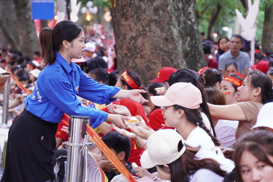 Khoang 6h, tai pho Hang Khay, cac tinh nguyen vien tien hanh phat nuoc va banh mien phi cho nguoi dan. Anh: Linh Trang - Trang Anh