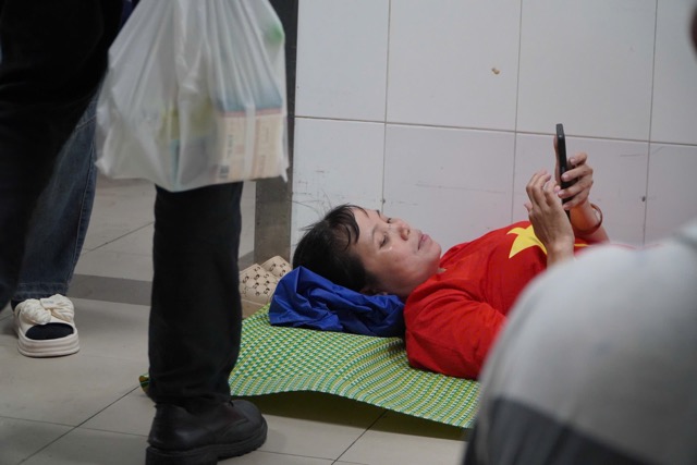 Nhieu nguoi tranh thu nghi ngoi o goc hanh lang benh vien