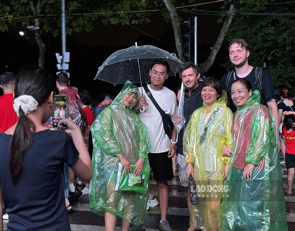 Khach quoc te va nguoi dan chup anh luu niem duoi mua. Anh: Nguyen Dat