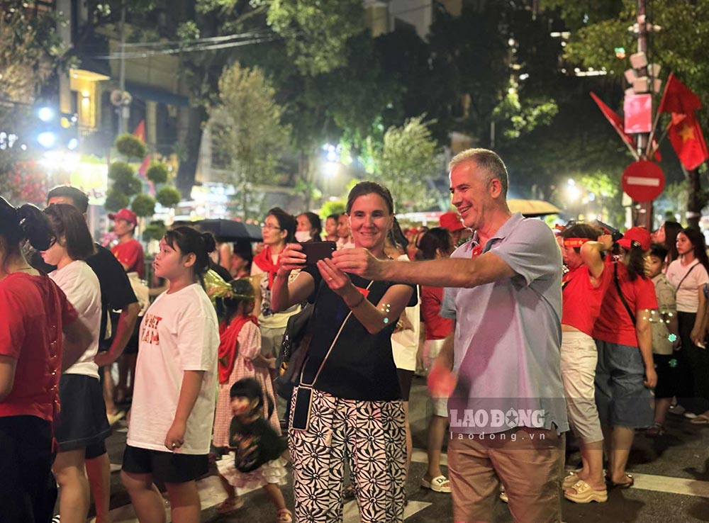 Teo va Laura duoc tang nhung chiec kep nho gan hinh Quoc ky Viet Nam khi hoa cung nguoi dan tren duong pho, dem truoc Tong duyet dieu binh, dieu hanh A80. Anh: Nguyen Dat