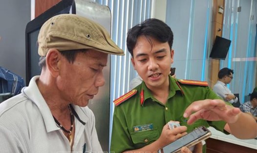Cán bộ công an hướng dẫn người dân thao tác xin cấp phiếu lý lịch tư pháp trên ứng dụng VNeID. Ảnh: TTXVN