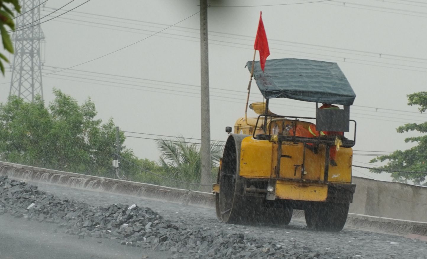 가랑비가 내려 노동자들이 여전히 비를 맞으며 고속도로 건설을 하고 있습니다.