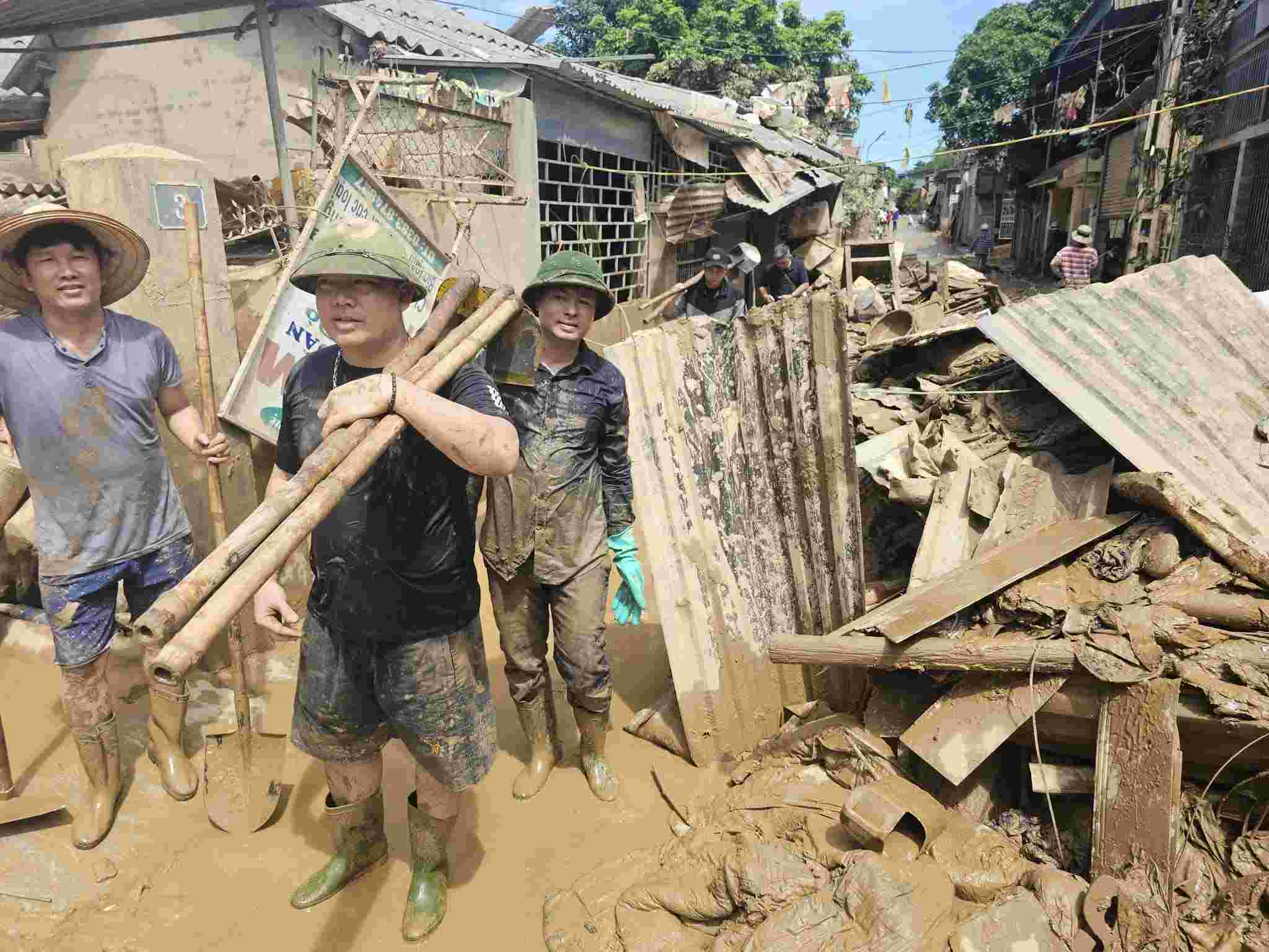Cac thay co giao mien xuoi vat lon voi bun dat giup truong ban khac phuc hau qua mua lu. Anh: Ngoc Anh