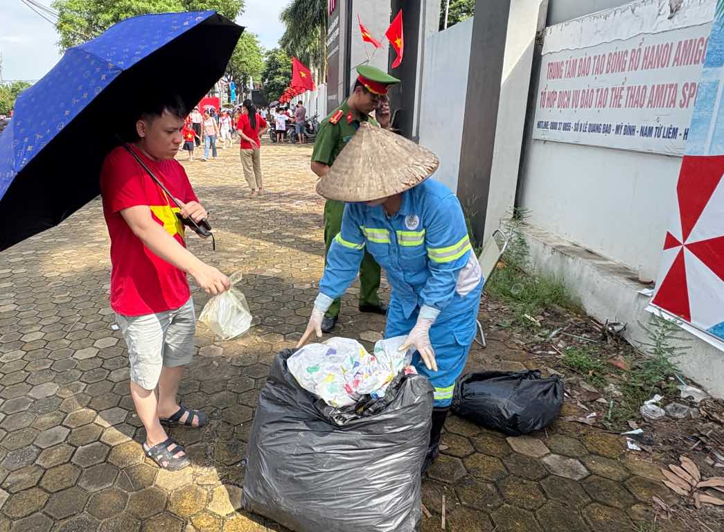 La gente limpia la basura despues de terminar de ver el equipo militar en la calle Le Quang Dao. Foto: Bao Han