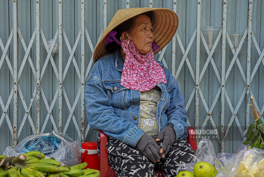 Cach do chung 50m, ba Nguyen Thi Lan Huong (64 tuoi) dang nup minh duoi mai ton nho trong cai nang hung huc de ban trai cay. Xung quanh, ngoai sap trai cay doi ban con co nhieu chai nuoc co lon, co mang theo da de giai nhiet. 