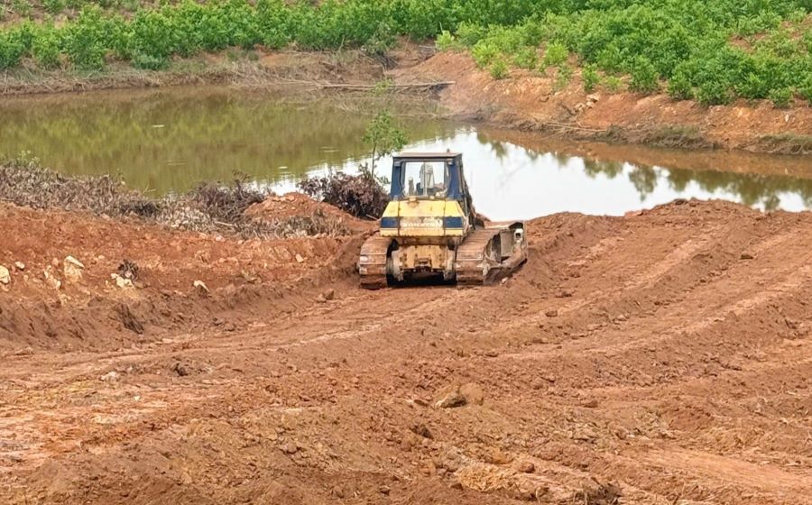 Máy ủi lấp đất xuống kênh thủy lợi. Ảnh: Hưng Thơ