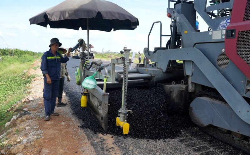 Workers constructing the asphalt paving of the Ring Road 4 parallel road section through Duong Hoa commune, Hanoi. Photo: Huu Chanh