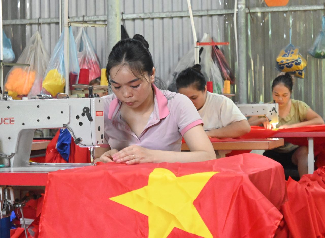 Les ouvriers d'un atelier de confection a Hanoï achevent assidûment chaque drapeau national avant la fete nationale du 2 septembre. Photo : Thanh Nhan