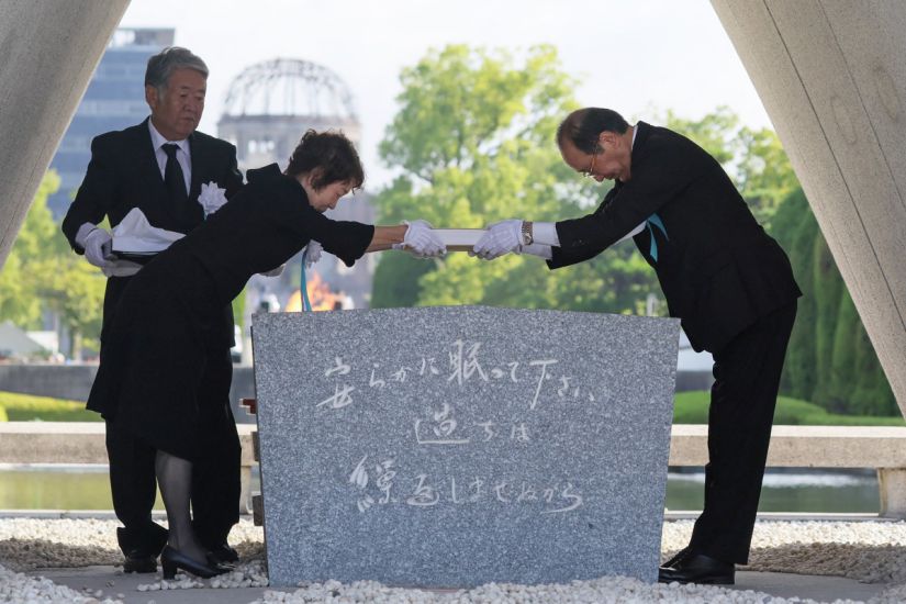 Hiroshima Mayor Kazumi Matsui (right) and representatives of the victims' relatives put a list of those killed by the bomb on a memorial stele at Hiroshima Peace Park on the morning of August 6, 2025. Photo: AFP