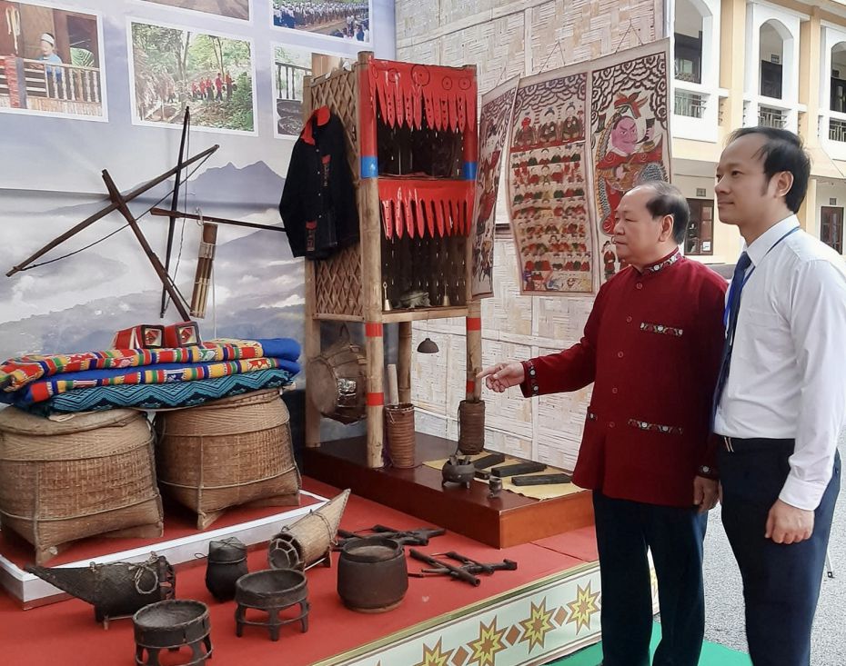 Bui Thanh Binh 씨(왼쪽)가 문화 유산 교류 및 홍보 행사에서 Muong 문화 전시 공간을 소개하고 있습니다. 사진: Thu Hang