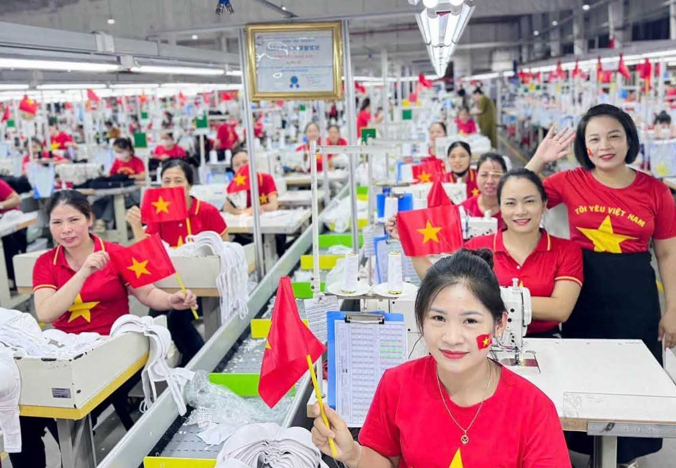 Trabajadores de Nghe An visten camisetas rojas con estrellas doradas y colgaron banderas nacionales para celebrar el 80 aniversario del Dia Nacional. Foto: Ngoc Anh